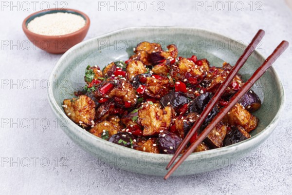 Fried eggplant, Chinese style, in sweet and sour sauce, with pepper and sesame seeds, in a green bowl