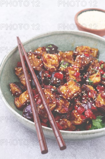Fried eggplant, Chinese style, in sweet and sour sauce, with pepper and sesame seeds, in a green bowl