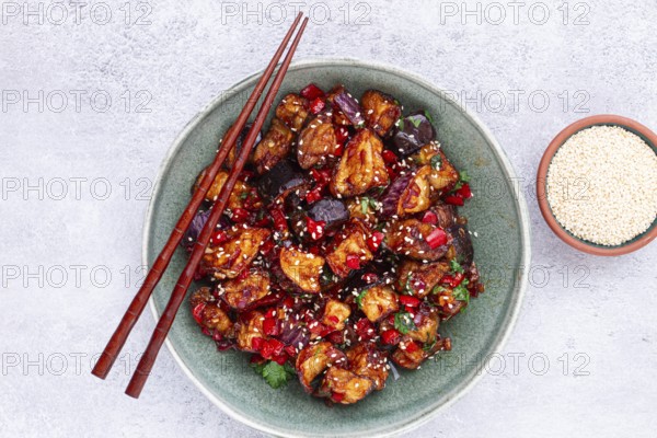 Fried eggplant, Chinese style, in sweet and sour sauce, with pepper and sesame seeds, in a green bowl