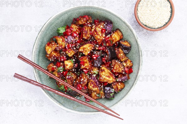 Fried eggplant, Chinese style, in sweet and sour sauce, with pepper and sesame seeds, in a green bowl