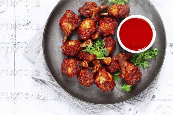 Crispy pieces of fried chicken, on a plate with sauce and herbs, in a modern kitchen environment, there are no people