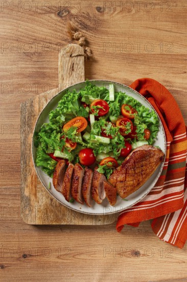 Delicious grilled duck breast served with fresh garden salad and cherry tomatoes at a rustic dining table
