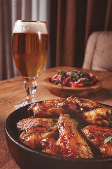 Delicious barbecue chicken wings, with French fries, salad and a refreshing drink, at a cozy table, there are no people