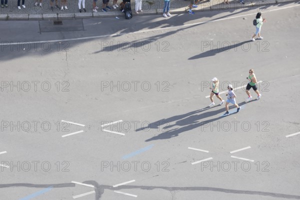 Runners with long shadows on the big star seen from the Victory Column at the 51st BMW Berlin Marathon 2025 on 21 September 2025