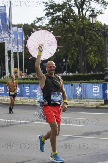 A runner with an umbrella on the Großer Stern at the 51st BMW Berlin Marathon 2025 on 21 September 2025