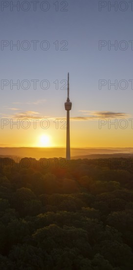 Sunrise over a television tower and forest, the golden sun is low in the sky, Stuttgart, Baden-Württemberg, Germany