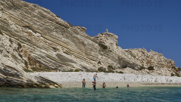 Group of people swimming in clear water in front of rocky beach landscape, White Cliffs, White Beach, Makri Aspronisi Island, Natura 2000 area, boat trip, Aspronisi, Lipsi, Dodecanese, Greek Islands, Greece