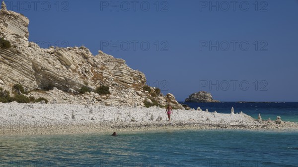 Rocks and a pebble beach meet turquoise waters under a clear sky, White Cliffs, White Beach, Makri Aspronisi Island, Natura 2000 area, boat trip, Aspronisi, Lipsi, Dodecanese, Greek Islands, Greece