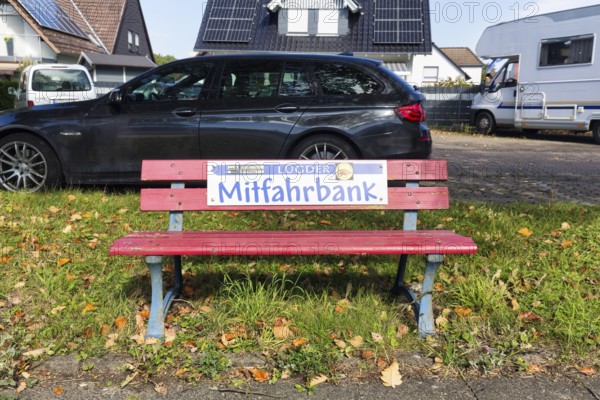 Red bench at the roadside, sign with inscription Mitfahrbank, Mitfahrerbank, symbol photo, carpool, free of charge, hitchhiking, ecology, traffic load, rural area, Lügde, Weserbergland, North Rhine-Westphalia, Germany