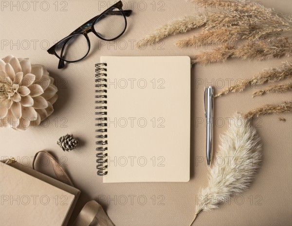 Flat lay composition featuring a beige spiral notebook, elegant pen, glasses, dried flowers, and ornamental elements arranged on a neutral background. Perfect for productivity, writing, journaling, or creative inspiration themes, AI generated