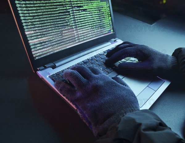 Cybersecurity threat depicted by gloved hands operating a computer, commands displayed on the screen. Represents hacking, data theft, and online crime concepts with a dramatic atmosphere, AI generated