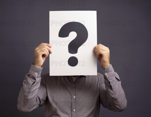 A person concealing their face while holding a question mark sign, symbolizing anonymity, mystery, or inquiry against a minimalistic dark background. Perfect for topics involving curiosity, problem solving, and identity, AI generated