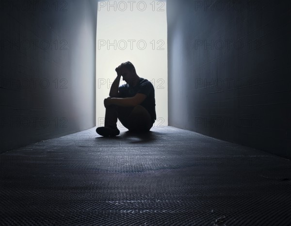 A silhouette of a person seated on the floor, conveying feelings of sadness and solitude against a softly lit window in a quiet place, AI generated