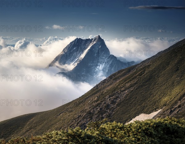 A stunning view of a snowy mountain peak rising above the clouds, with a blue sky background. Capturing a tranquil moment in nature's beauty, evoking feelings of serenity and wonder, AI generated