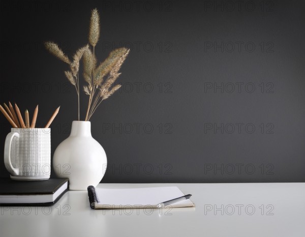 A clean and modern office workspace featuring a pen holder, notebook, and ceramic vase against a dark wall, AI generated