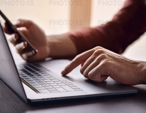 A man in a professional office environment multitasking with a smartphone and laptop, conveying productivity, technology integration, and modern working practices, AI generated