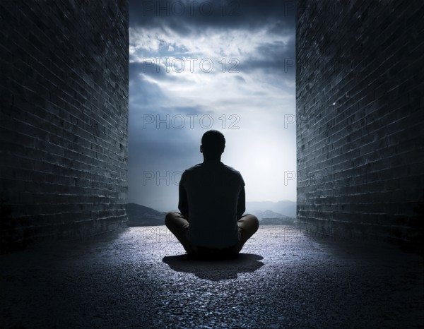 Silhouette of a person sitting alone within a brick archway, observing a peaceful and scenic cloudy horizon, evoking feelings of solitude, introspection, and calmness, AI generated