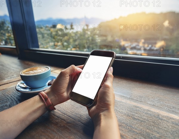 A person holding a smartphone at an outdoor cafe amidst a vibrant and lively urban setting. The image captures a relaxed moment with modern technology interaction and a scenic cityscape, AI generated