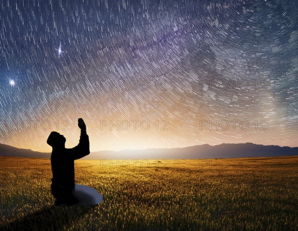 A man kneels in peaceful reflection under the vibrant Milky Way galaxy at sunset in an open natural setting, making prays, AI generated