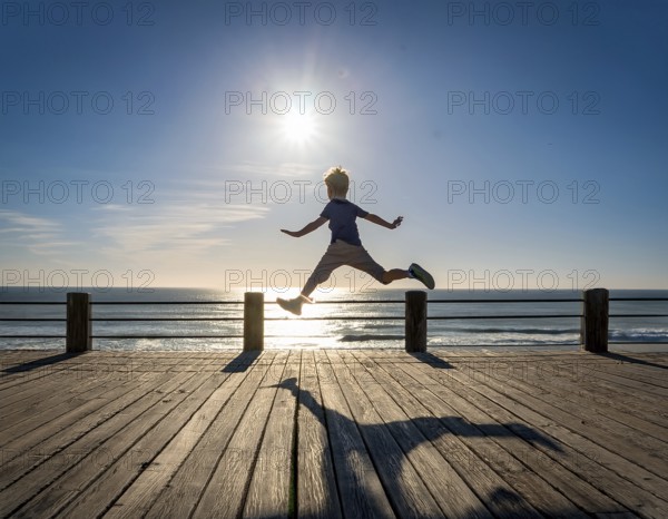 Silhouette of an individual joyfully leaping during a dramatic sunset, symbolizing freedom. An uplifting scene of youthfulness, optimism, and outdoor activity in a picturesque natural setting, AI generated
