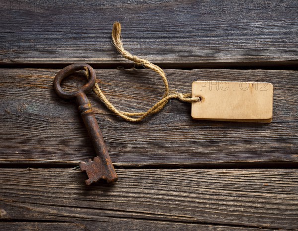 A close-up of an ornate vintage key with a blank label attached, resting on a brown surface under soft, warm light, evoking a sense of mystery, history, and curiosity, AI generated