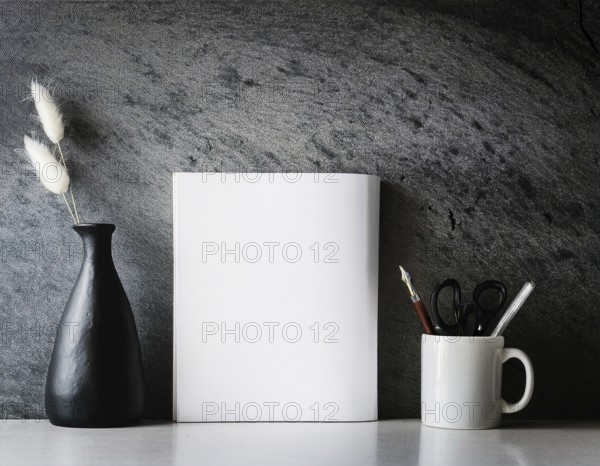 A clean and modern office workspace featuring a pen holder, notebook, and ceramic vase against a dark wall, AI generated