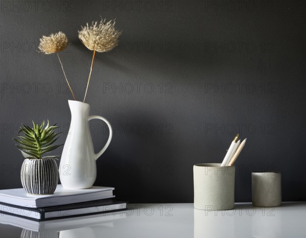 A clean and modern office workspace featuring a pen holder, notebook, and ceramic vase against a dark wall, AI generated