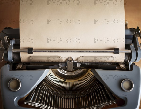 View from above of a retro typewriter equipped with a blank paper sheet, representing creativity, literary work, and nostalgia for traditional written communication methods, AI generated