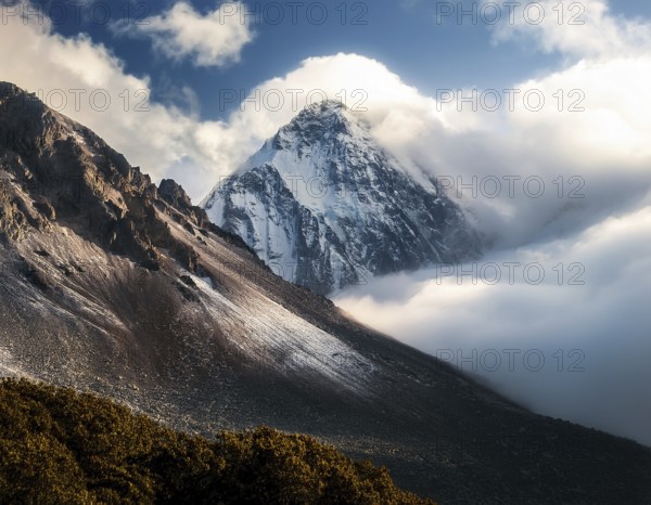A stunning view of a snowy mountain peak rising above the clouds, with a blue sky background. Capturing a tranquil moment in nature's beauty, evoking feelings of serenity and wonder, AI generated