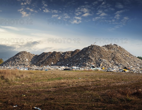A scenic evening view of a large landfill site with piles of collected waste surrounded by open fields and a clear sky, emphasizing environmental issues and sustainable waste management challenges, AI generated