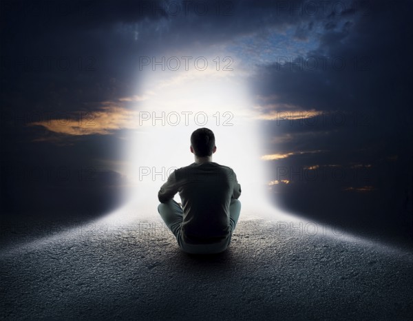 An individual sits in quiet contemplation near the ocean during sunset, surrounded by dramatic clouds, evoking feelings of peace, introspection, and connection to nature, AI generated