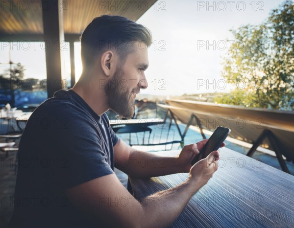 A person holding a smartphone at an outdoor cafe amidst a vibrant and lively urban setting. The image captures a relaxed moment with modern technology interaction and a scenic cityscape, AI generated