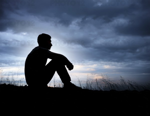 A silhouette of a person seated on the floor, conveying feelings of sadness and solitude against a softly lit window in a quiet place, AI generated