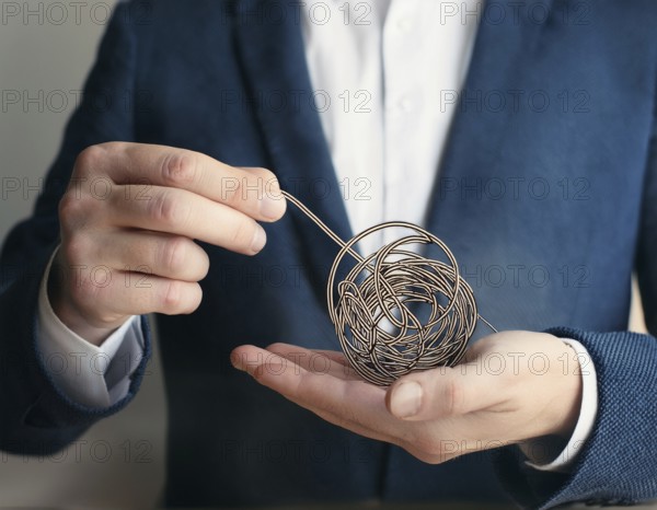 A close-up of a professional ipresenting a piece of intricate, tangled wire, symbolizing complexity, solution-finding, and creative problem-solving in a business or conceptual context, AI generated