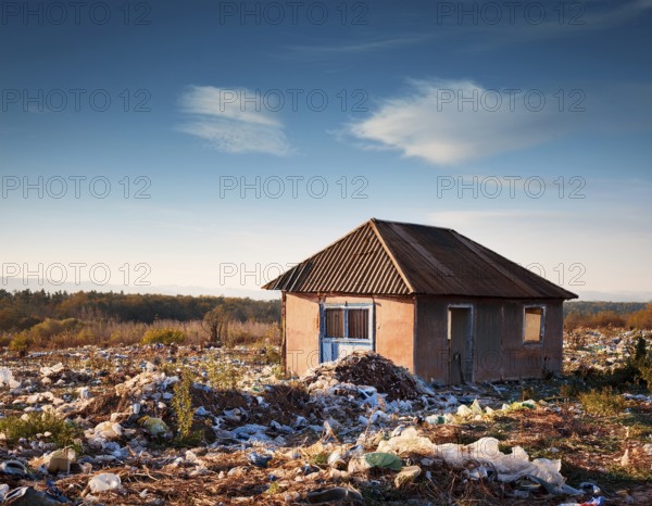An abandoned house sits amidst scattered garbage in a deserted rural area, conveying environmental degradation. The scene embodies neglect, waste accumulation, and ecological crisis in a starkly barren setting, AI generated
