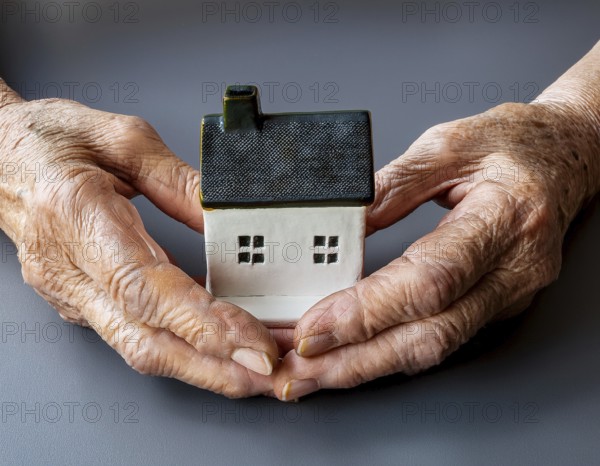Elderly hands gently cradle a small house model, representing themes of home, security, care, and connection. The image conveys warmth, protection, and the importance of family and stability, AI generated