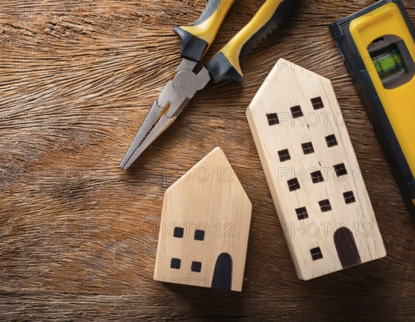A detailed layout of miniature wooden houses accompanied by various tools on a textured wooden surface, portraying concepts of construction, renovation, craftsmanship, and home improvement, AI generated