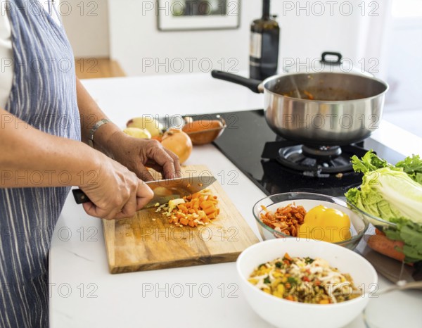 A cozy kitchen scene showing only hands of a couple preparing food, chopping vegetables, and stirring pot, AI generated