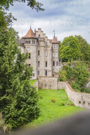 A castle surrounded by trees and stone walls, with a clear sky in the background, Lichtenstein Castle, Lichtenstein, Swabian Alb, Germany