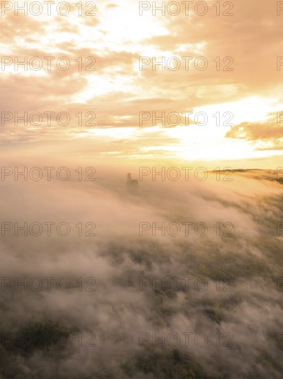 Castle appears through thick fog, surrounded by golden sky light, Lichtenstein Castle, Lichtenstein, Swabian Alb, Germany