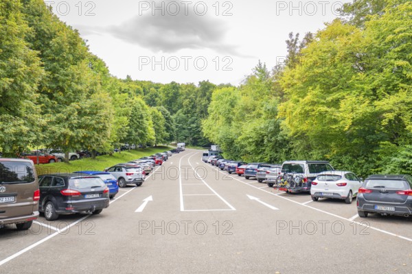 A long car park, lined with many cars and lush green trees, Lichtenstein Castle, Lichtenstein, Swabian Alb, Germany