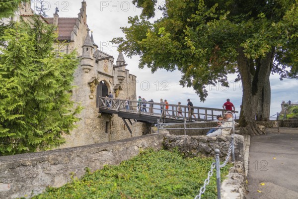 People on a stone bridge leading to a castle, surrounded by trees, Lichtenstein Castle, Lichtenstein, Swabian Alb, Germany