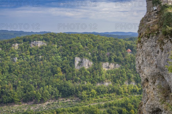 Lush forest landscape with steep rock faces and a vast green panorama in the distance, Lichtenstein Castle, Lichtenstein, Swabian Alb, Germany