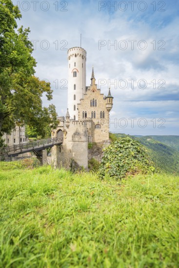 Medieval castle on a grassy cliff, surrounded by a picturesque landscape and dramatic sky, Lichtenstein Castle, Lichtenstein, Swabian Alb, Germany