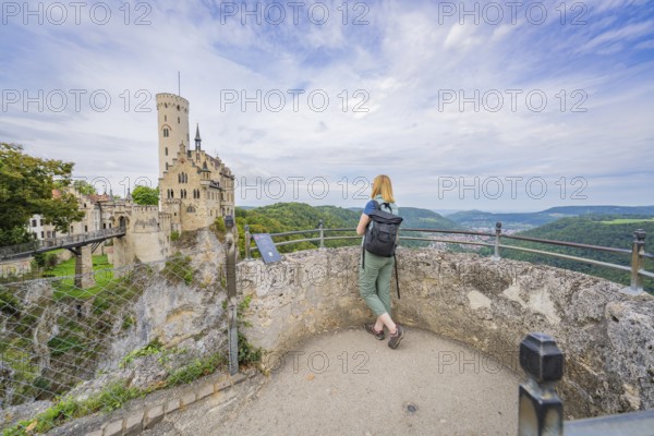 Person admires castle and wide, wooded landscape from the vantage point, Lichtenstein Castle, Lichtenstein, Swabian Alb, Germany