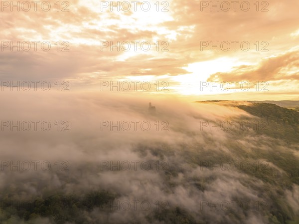 Aerial view of a fog-covered forest at sunset with dramatic sky, Lichtenstein Castle, Lichtenstein, Swabian Alb, Germany