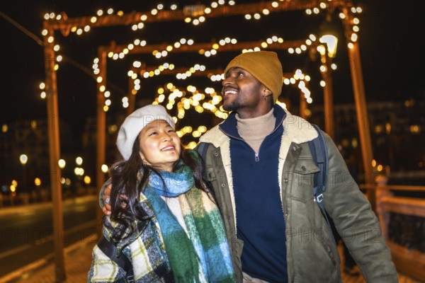 Multiethnic couple enjoying the enchanting glow of christmas lights while strolling through a winter city, embracing the festive spirit