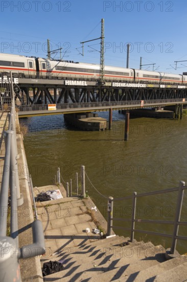 Dilapidated staircase to Oberehafen and Ericusgraben with a view of the Oberhafen bridge over which an ICE train runs, Hamburg, Germany
