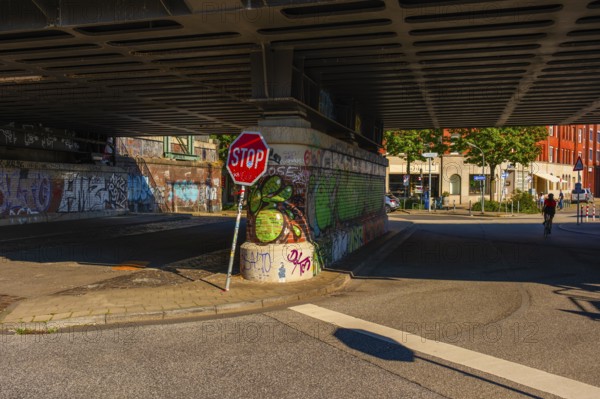 View of parts of a road leading under the Oberhafen Bridge and of the abutment painted with graffiti, people as gnomes, Hamburg, Germany