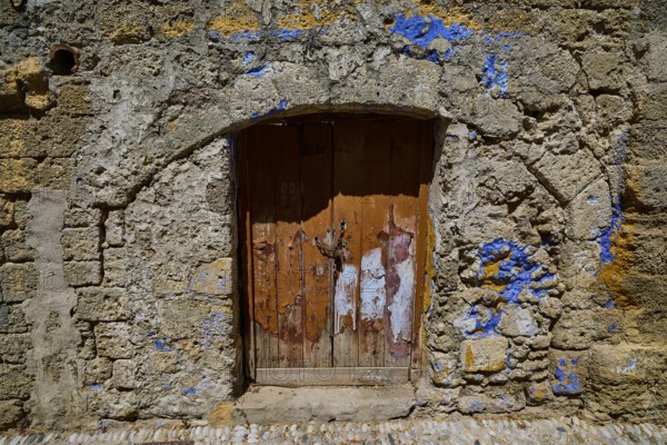 Weathered wooden door in an ancient stone wall decorated with blue accents, Turkish Quarter, Rhodes Old Town, Rhodes Town, Rhodes, Dodecanese, Greek Islands, Greece